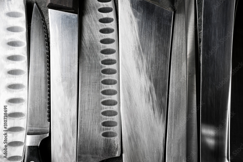 Professional kitchen knives texture on dark stone background. Creative layout. Chef, restaurant or kitchen concept. Top view, copy space