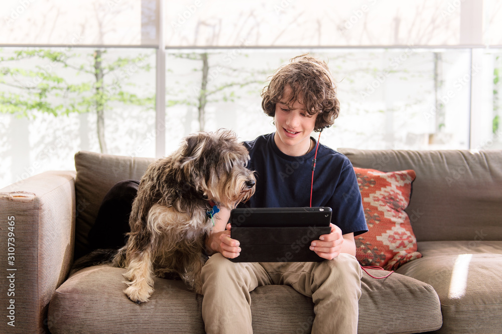Dog and a teenage boy sitting together indoors Dog and a teenage boy sitting together indoors