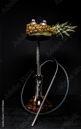 hookah on a pineapple, pine branches in a flask and red syrup. beautiful metal shisha on black isolated background