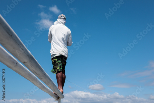 Man standing on a bamboo pole against a clear blue sky