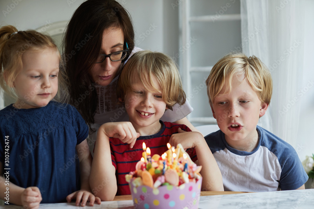 Woman and children gathered round a birthday cake Woman and children gathered round a birthday cake