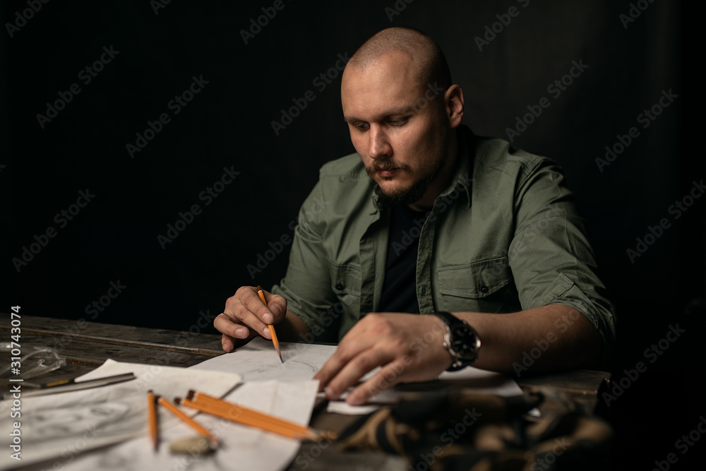 Focused artisan creating draft of metal sculptures Focused artisan creating draft of metal sculptures