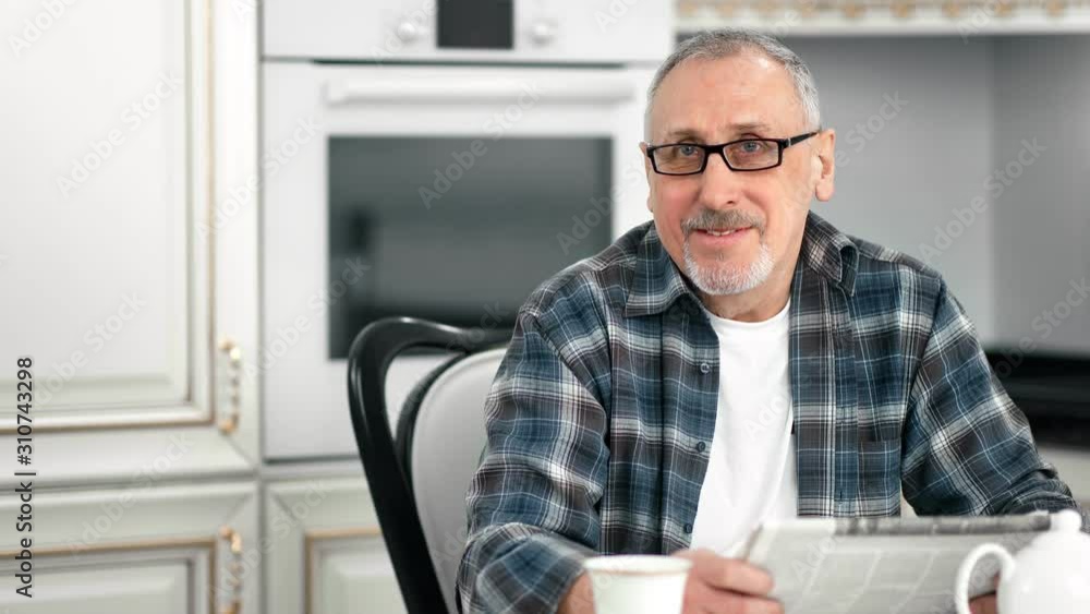 Portrait of casual elderly bearded man posing at kitchen smiling looking at camera Portrait of casual elderly bearded man posing at kitchen smiling looking at camera