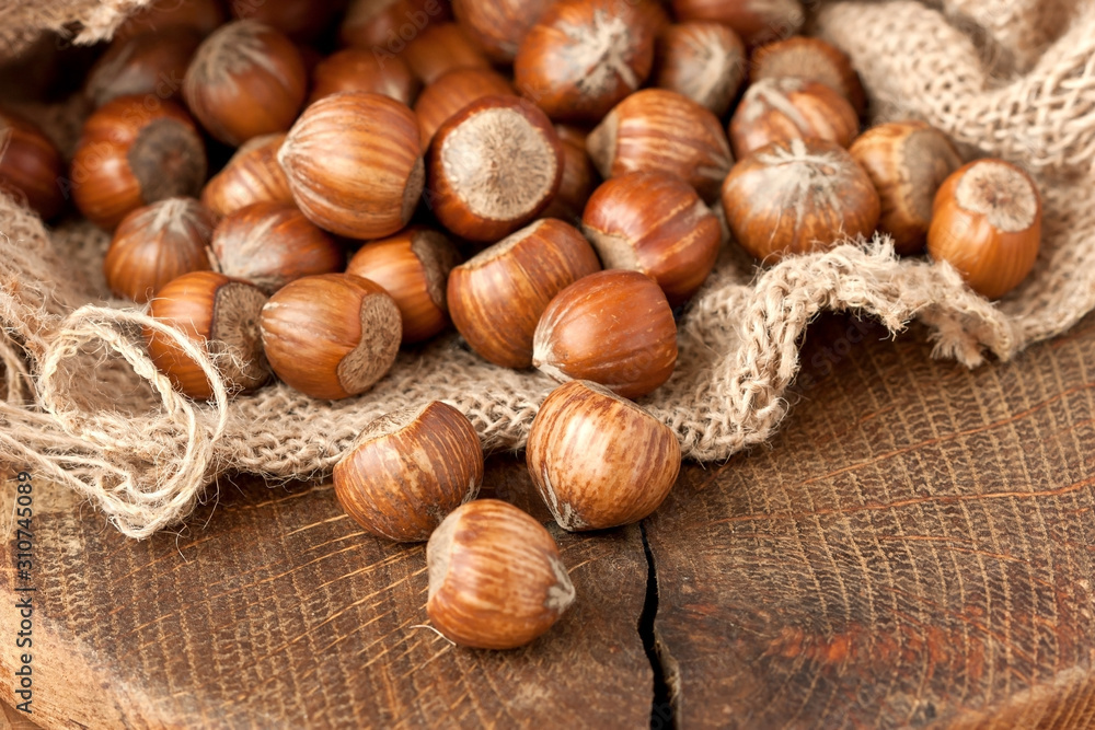 Burlap with hazelnuts on wooden background, selective focus Burlap with hazelnuts on wooden background, selective focus