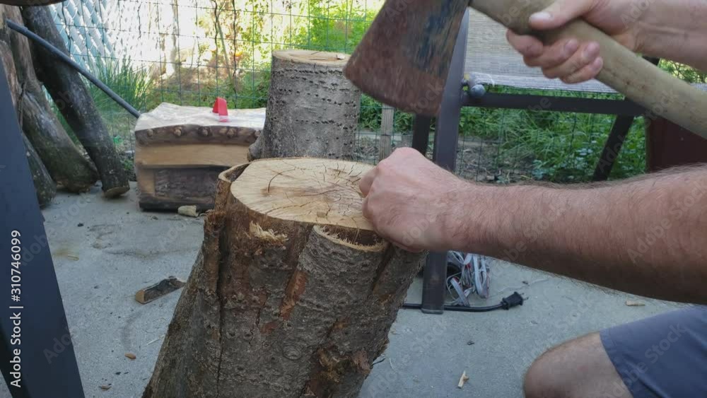 Man using Ax to chop small pieces of wood on stub preparing wood chips for smoker. Man using Ax to chop small pieces of wood on stub preparing wood chips for smoker.