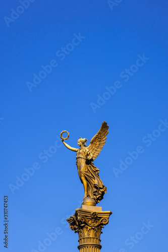 Gold lady monument on a blue sky background, Prague, vertical