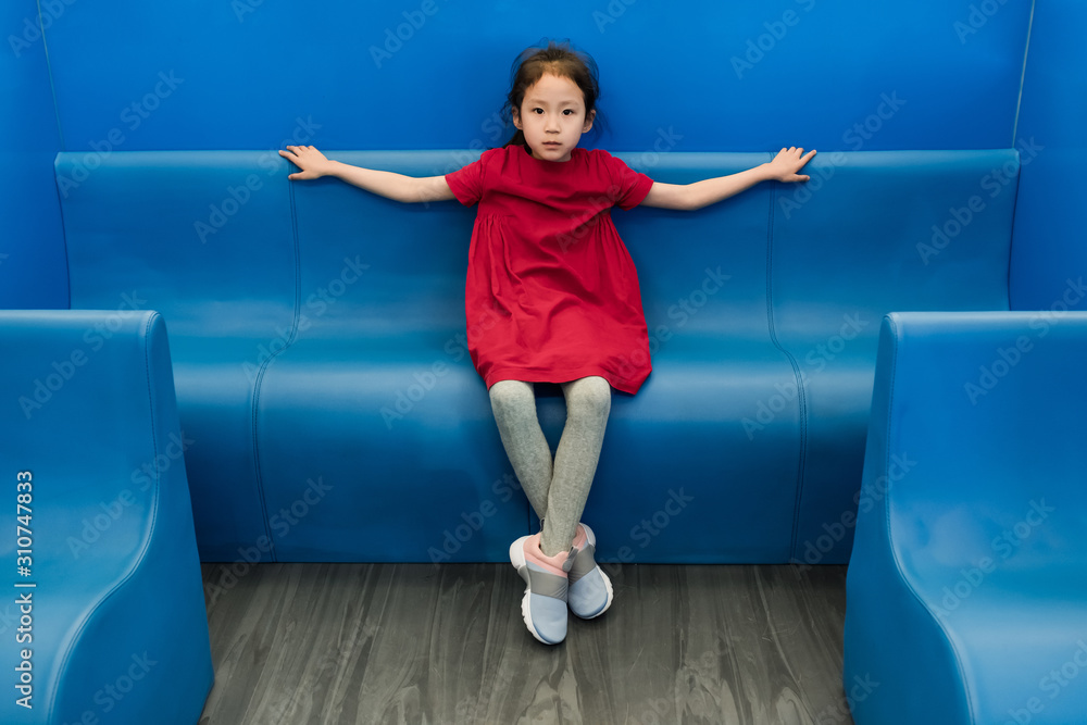 Cute little girl sitting on a blue bench Stock Photo | Adobe Stock