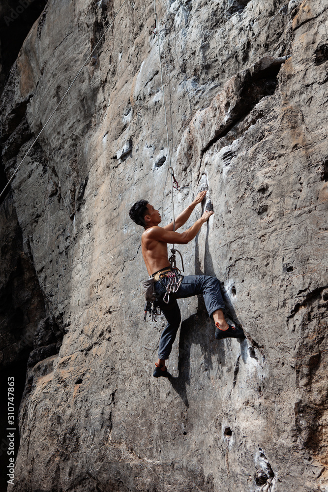 Muscular man training on mountain wall Muscular man training on mountain wall