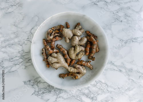 Fresh turmeric and ginger in bowl on marble table photo