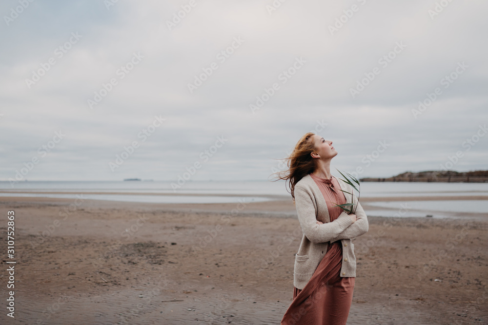 Thoughtful romantic young woman on the shore of the bay on a cloudy windy day. Thoughtful romantic young woman on the shore of the bay on a cloudy windy day.