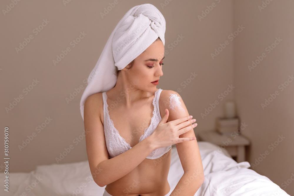 Beautiful young woman applying cosmetic lotion on her shoulders Beautiful young woman applying cosmetic lotion on her shoulders