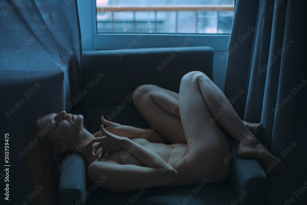 the girl lies without clothes on the armchair and covers herself with her hands the girl lies without clothes on the armchair and covers herself with her hands