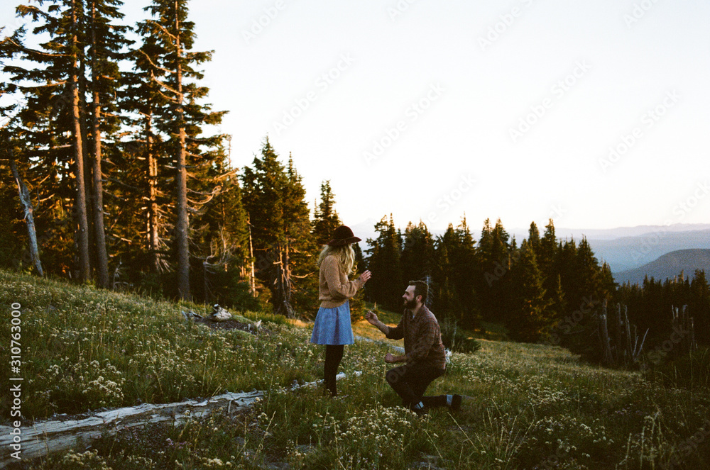 Man proposing to his girlfriend on top of the mountain Man proposing to his girlfriend on top of the mountain