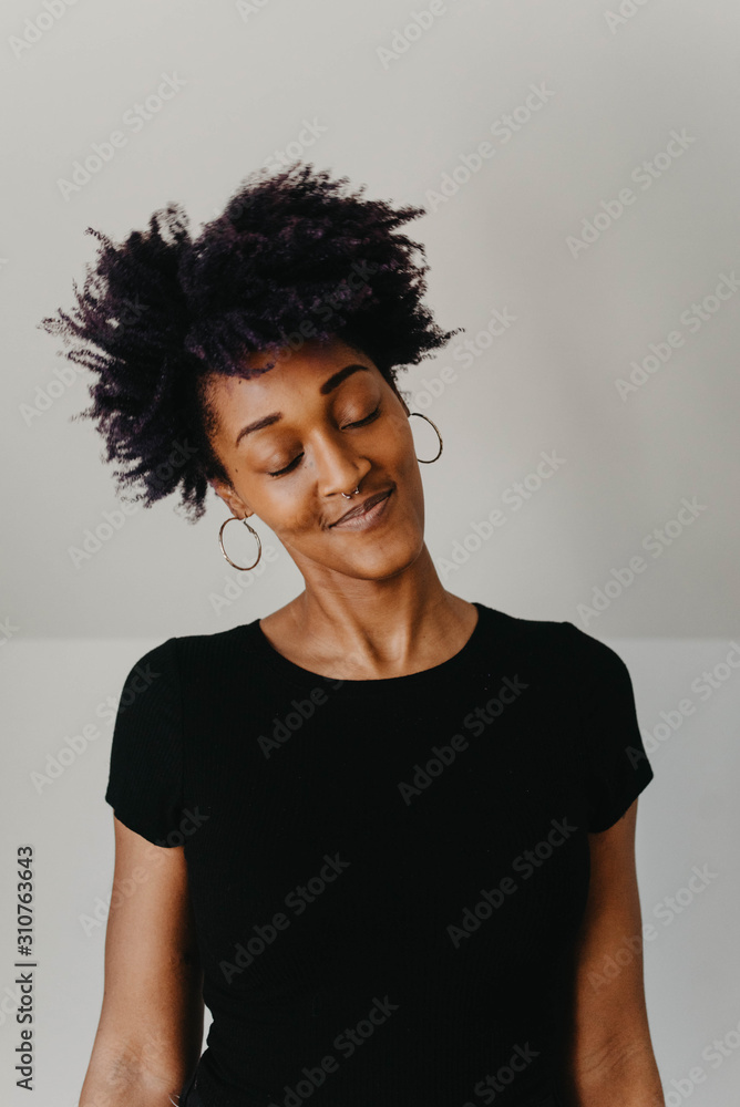 A beautiful african american woman with purple hair against a white wall A beautiful african american woman with purple hair against a white wall