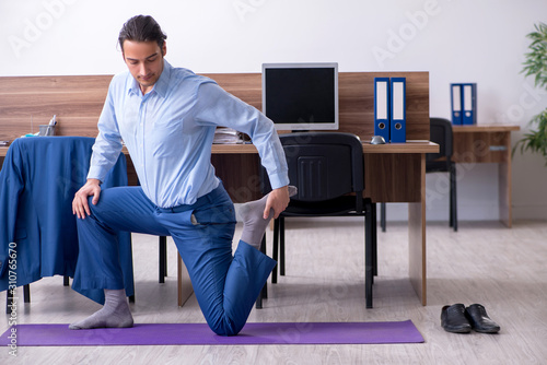 Young handsome businessman doing exercises at workplace © Elnur
