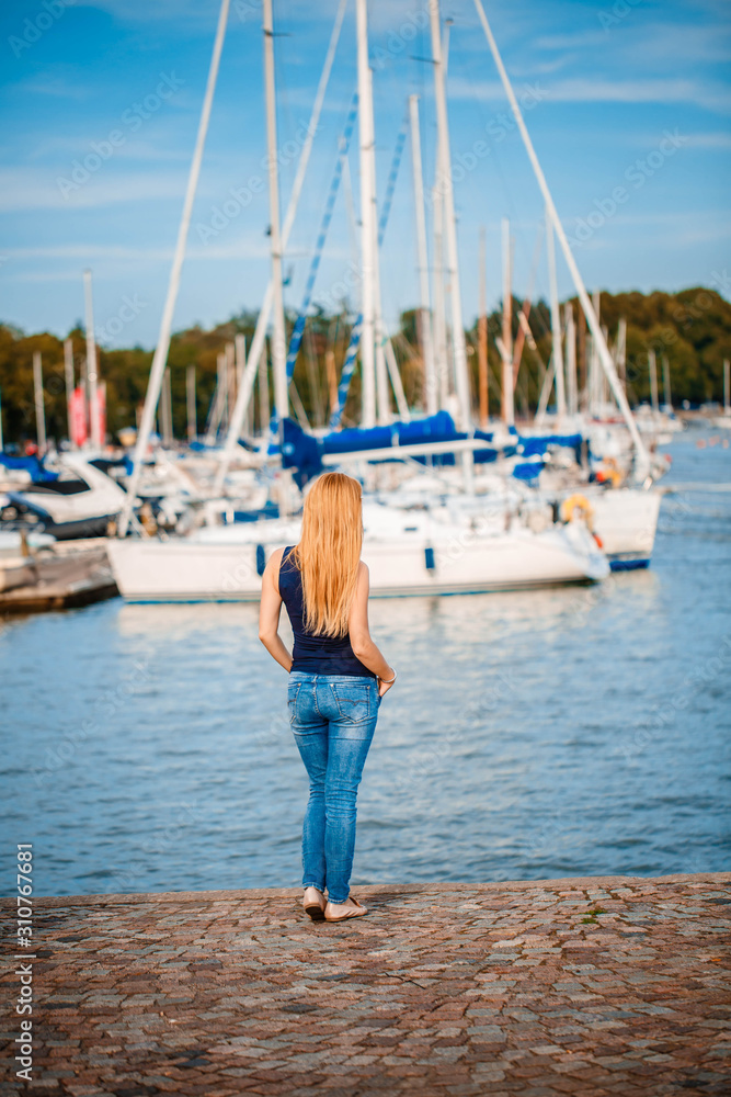 girl with red hair sits back on a yachting pier. Helsinki
