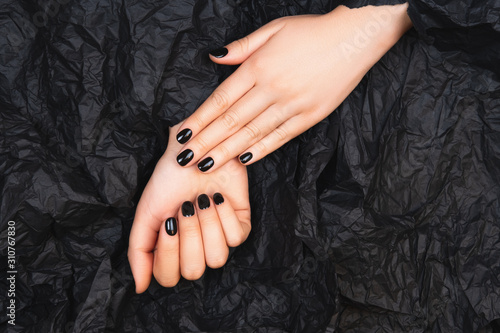 Black manicure with crumpled papet. Flat lay style.
