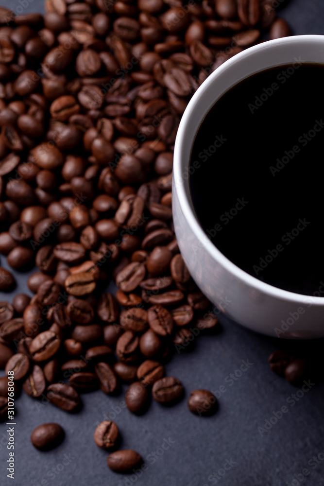 Fototapeta premium Roasted coffee beans and cup of coffee on granite background