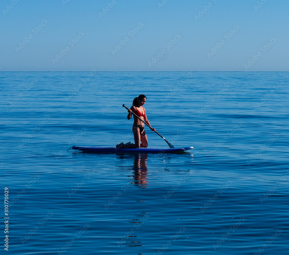 Close-up Asian woman kneeling on standup paddle board Sea of Cortez.