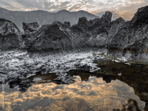 clouds reflecting in pool by rocks
