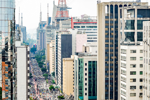 Aerial view of Paulista avenue full of people walking on the street and the tall buildings of the avenue. Commercial center at downtown of Sao Paulo SP, Brazil.