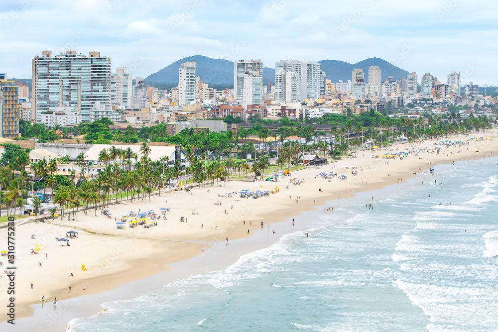 Aerial view of the Cove Beach at Guaruja SP Brazil. People on the beach, the sand, sea waves and the city on background. Place known as Praia da Enseada. Brazilian coastal city.