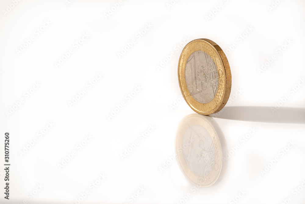 Aufgestellte Euro Münze auf einer weißen Unterlage mit Spiegelung