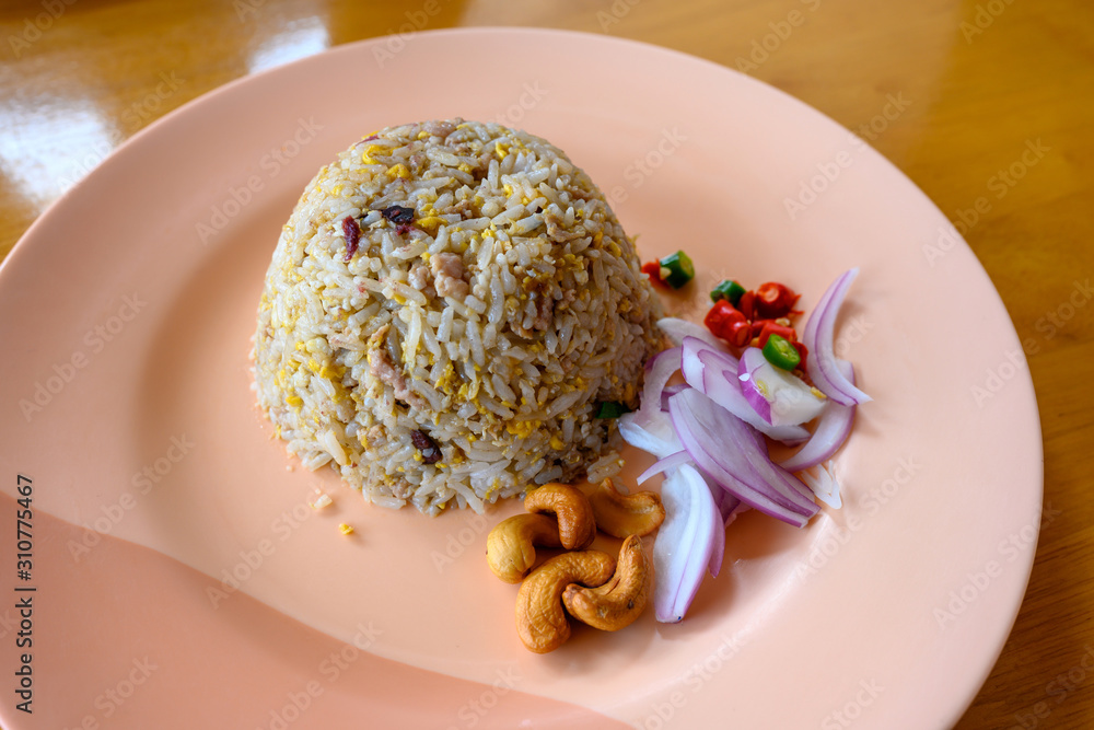 Salted chinese black olive fried rice with minced pork In a light red dish on an orange wooden table Is a popular Asian food in Thailand.