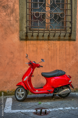 A pic of a red scooter parked under a window