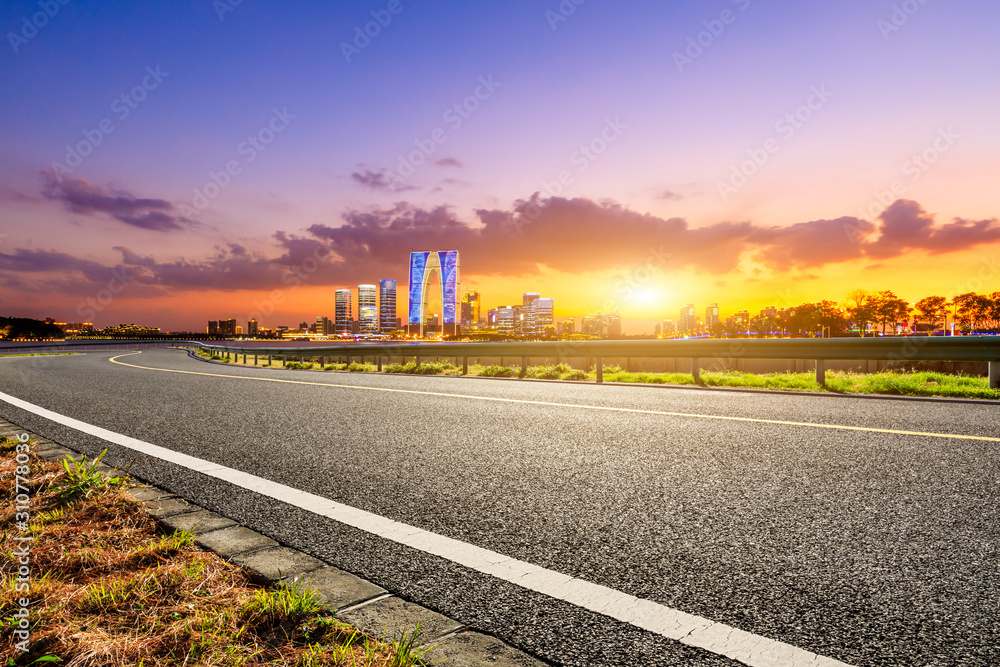 Obraz premium Asphalt road and Suzhou city skyline with beautiful colorful clouds at sunset.