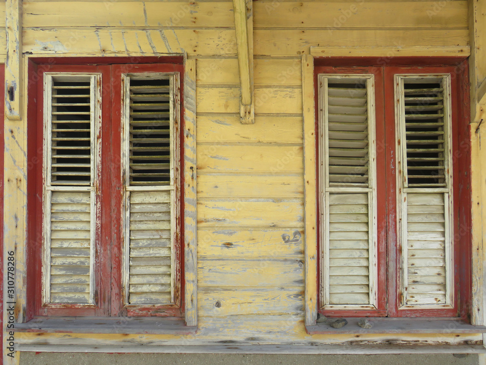 Rusted red and white windows over yellow facade. Tropical construction. Martinique, Antilles. French West Indies