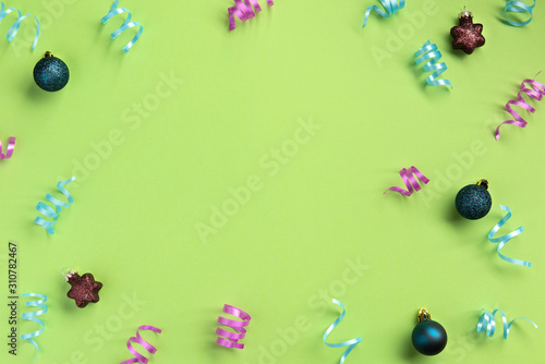 Christmas, New Year, winter concept. Colorful serpentine and balls, on green background. Flat lay, top view, copy space.