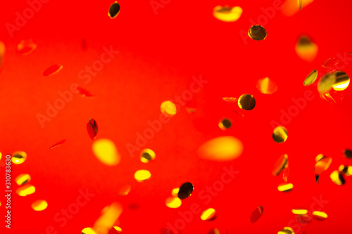 Golden falling confetti on red background. Holiday concept.