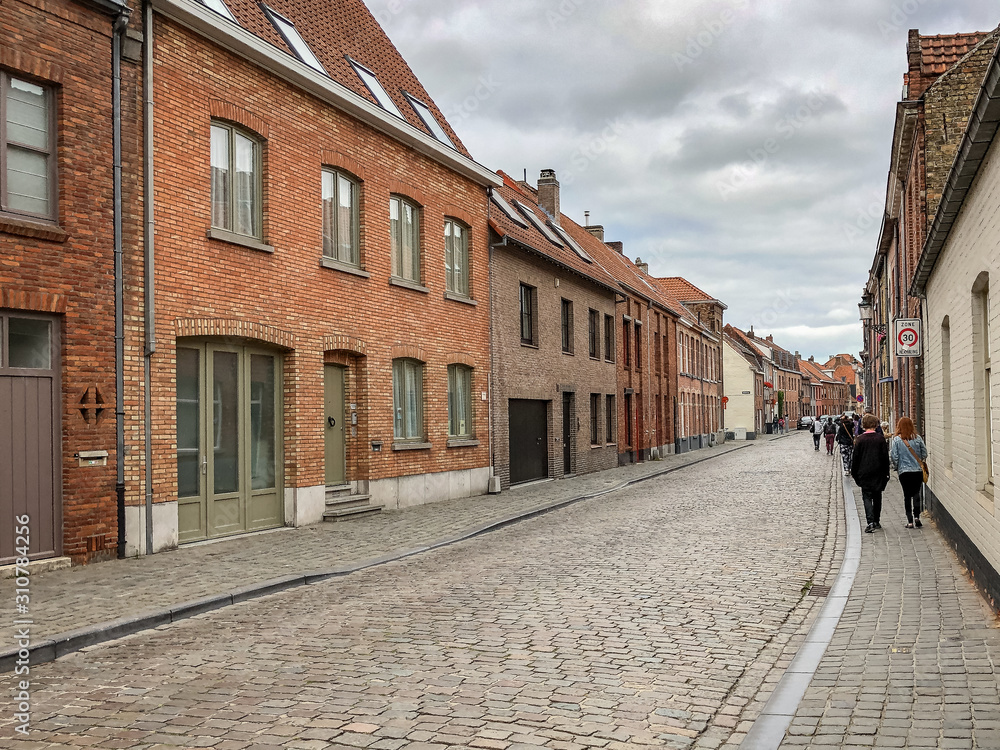 People Walking Along a Cobblestone Street in Bruges