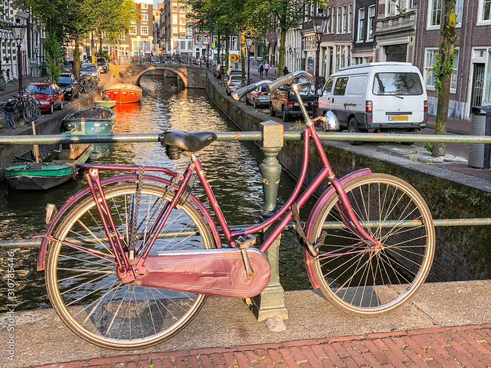 Red Bicycle Leaning on Canal Railing in Amsterdam