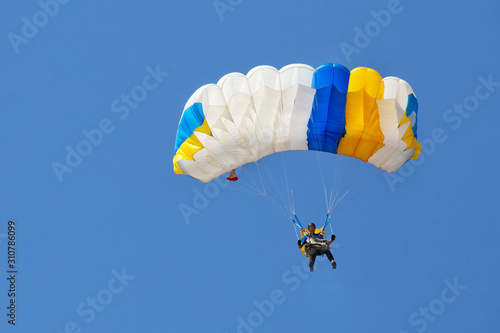 Photo Skydiver descends under canopy of a parachute