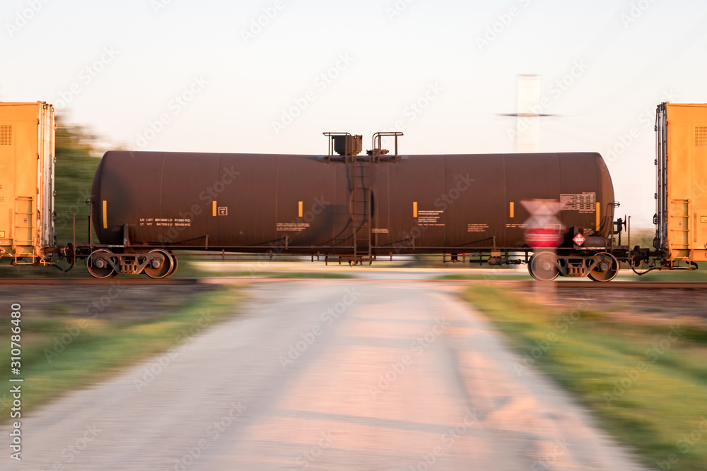 Black Tank Car Speeding Through Road Crossing at Sunset Black Tank Car Speeding Through Road Crossing at Sunset