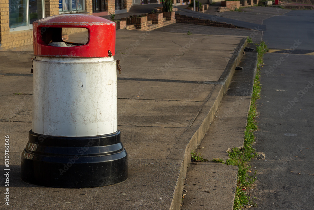 red white and black trash can on concrete pavement red white and black trash can on concrete pavement