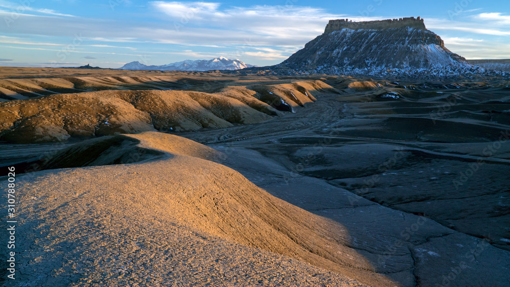 Factory Butte at sunset in the Caineville desert with light across the landscape.