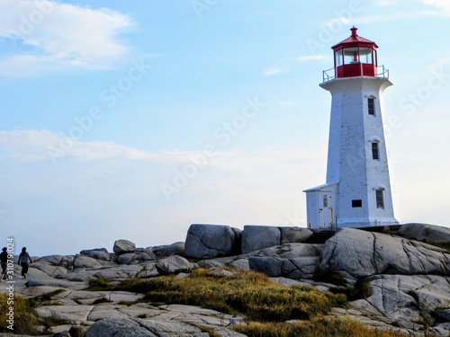 Visitors walking towards Peggys Point Lighthouse, also known as Peggys Cove Lighthouse, an active lighthouse and an iconic Canadian image.