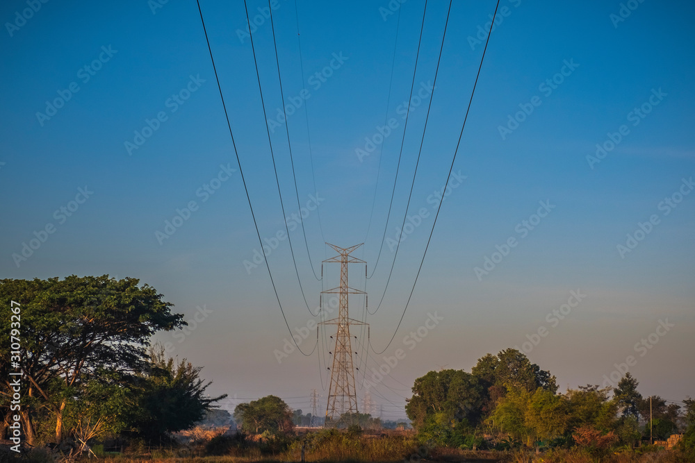 Electric pole and electric cable on the field in the countryside with blue sky.