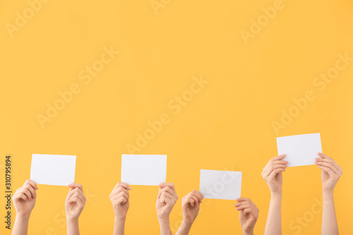 Hands of voting people with ballots on color background
