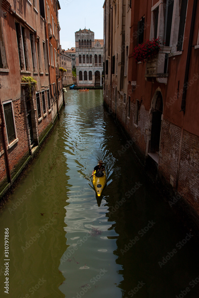 Person in Kayak Paddling Through Canal in Venice