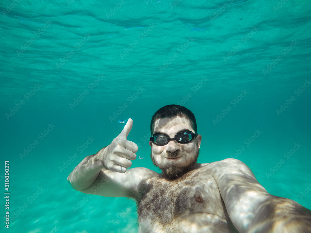 man under water with glasses showing thumb up. Active rest.