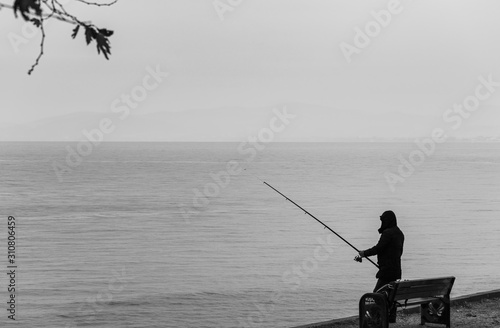 Silhouette of fisherman at sunset. Black and white seascape. Silhouette of pe...
