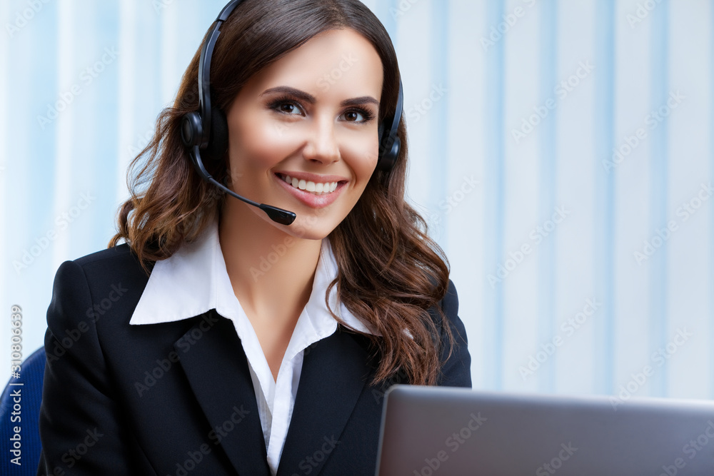 Portrait picture of customer support female phone operator or sales agent in headset and confident black suit, working with laptop at office workplace. Consulting and assistance service call center. Portrait picture of customer support female phone operator or sales agent in headset and confident black suit, working with laptop at office workplace. Consulting and assistance service call center.