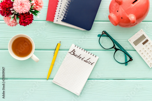 Bucket list. Blank notebook to write goals and wishes on green wooden office desk top-down