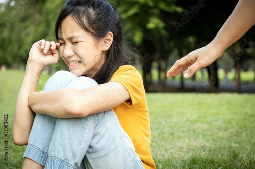 The hand of wishful woman is reaching out to care,help a lost girl,sad asian people sit and crying,get lost or stray from her parents in a city park, missing their parents,grieving, despair, sorrow photo