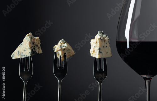 Fotografi Pieces of blue cheese on a forks and red wine.
