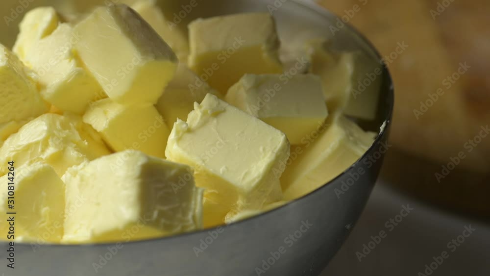Close up adding cube cut butter to a metal bowl. Close up adding cube cut butter to a metal bowl.